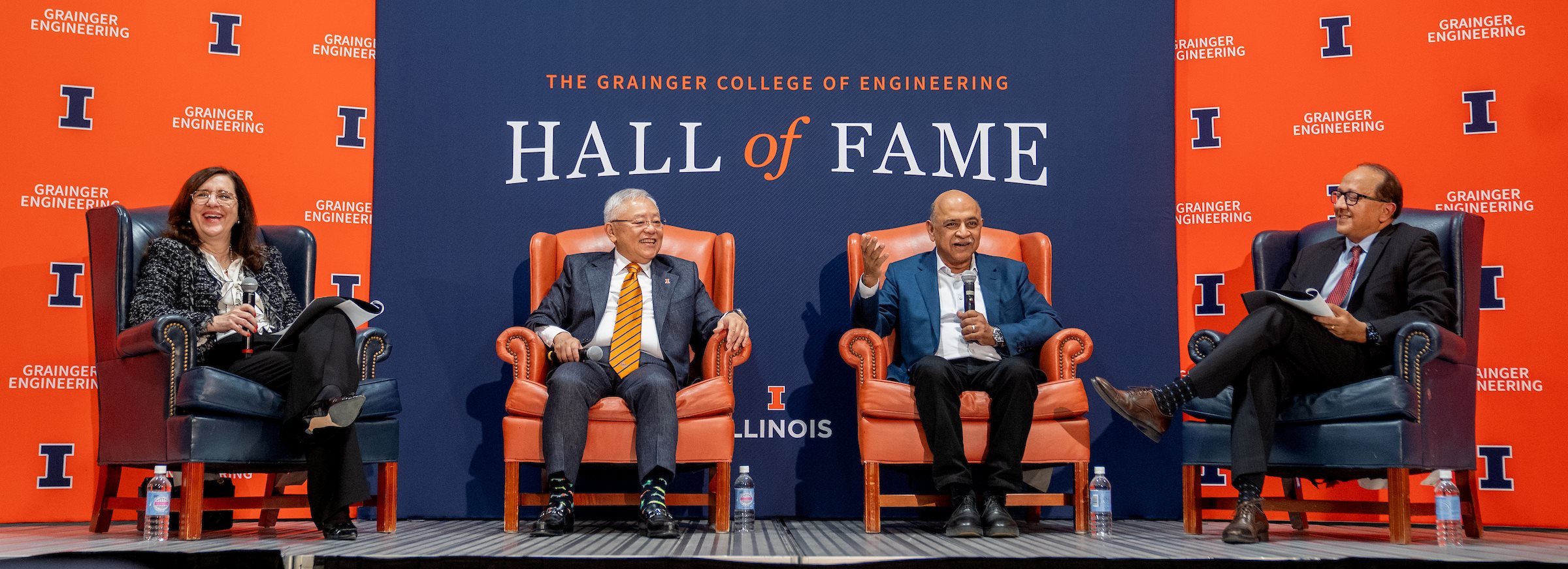 Mary McDowell, Sidney Lu, Arvind Krishna and Rashid Bashir sitting on a stage in front of orange and blue backdrops with Grainger Engineering and Hall of Fame branding.
