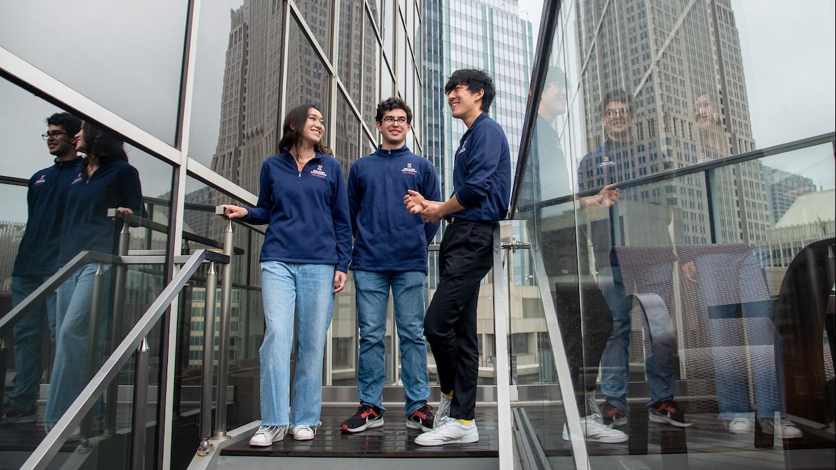 Three City Scholars students at the Illini Tower in Chicago, with skyscrapers in the background