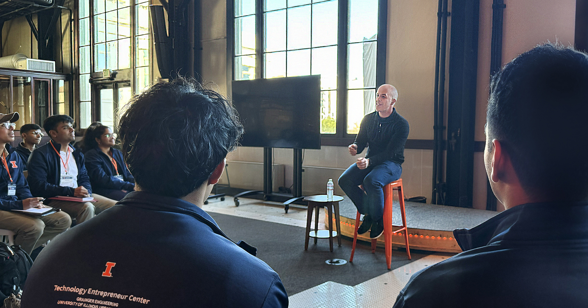 Pete Koomen talks to students wearing Technology Entrepreneur Center branded clothing at Y Combinator&rsquo;s San Francisco headquarters.