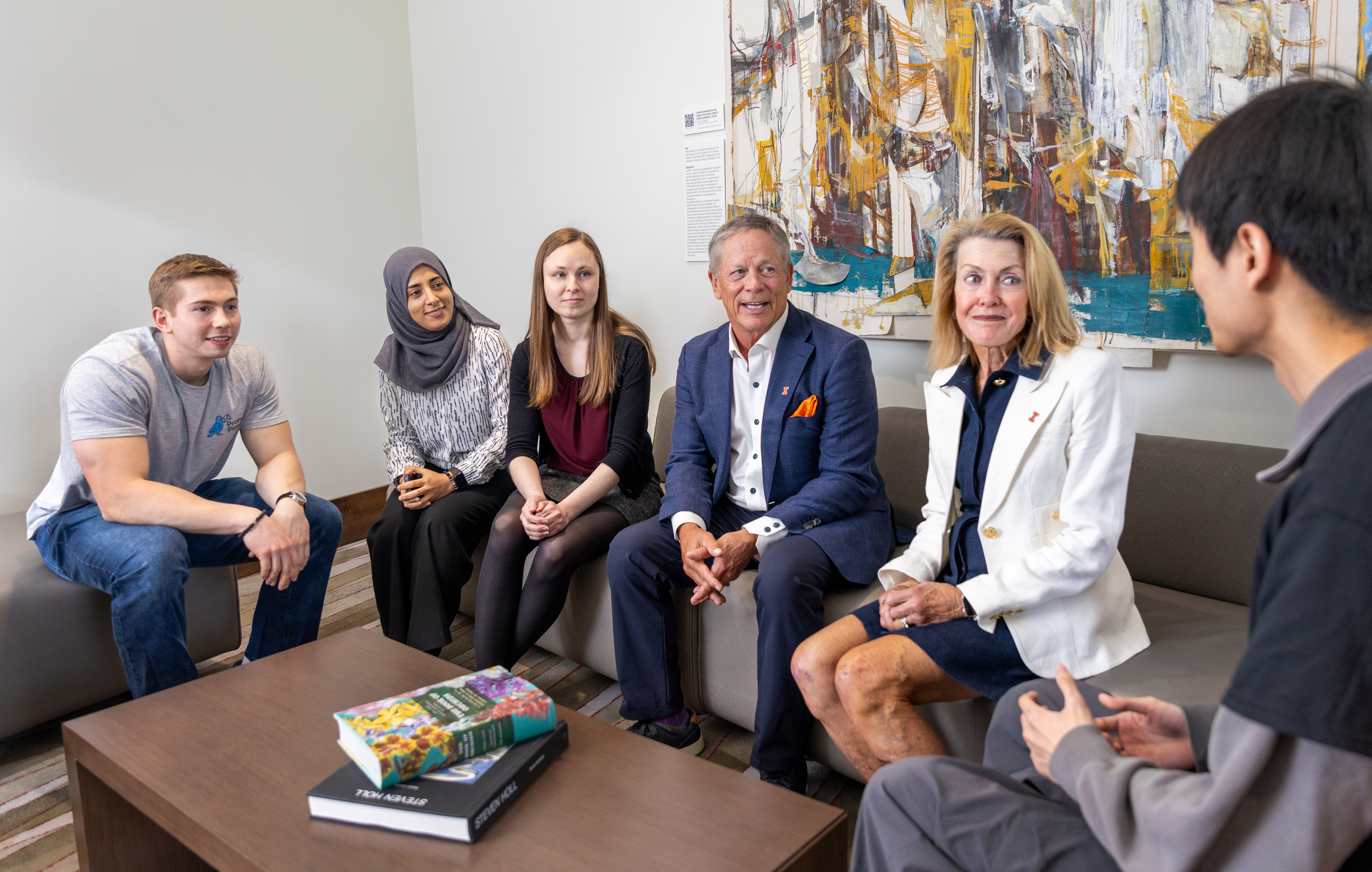 Five students sitting on couches and chairs in conversation with Richard and Gayle Landuyt.