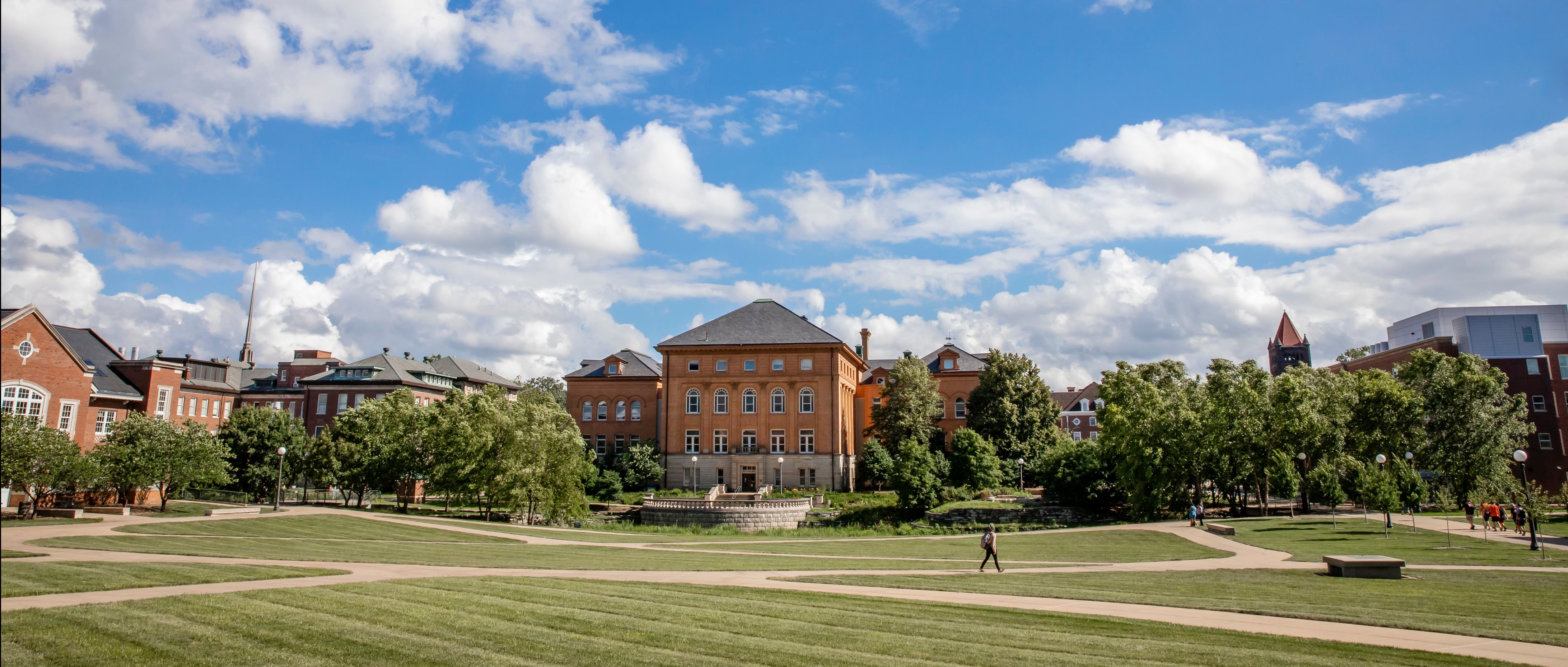 The back of Engineering hall from across Bardeen quad with a lone student walking on a sunny day.