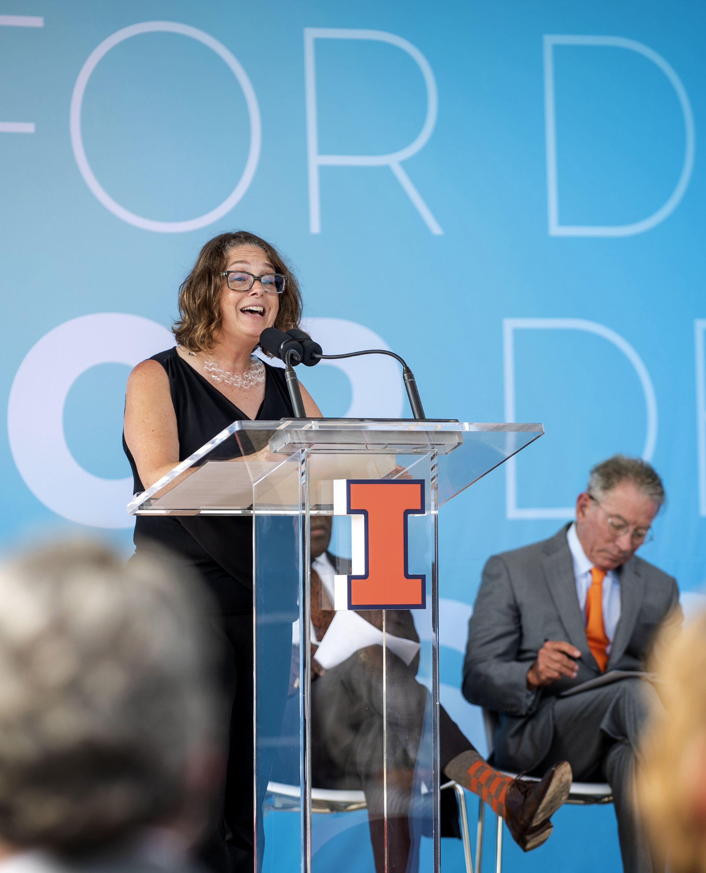 Rachel Switzky takes the podium at the SCD celebration event as she introduces Tom Siebel, sitting right.