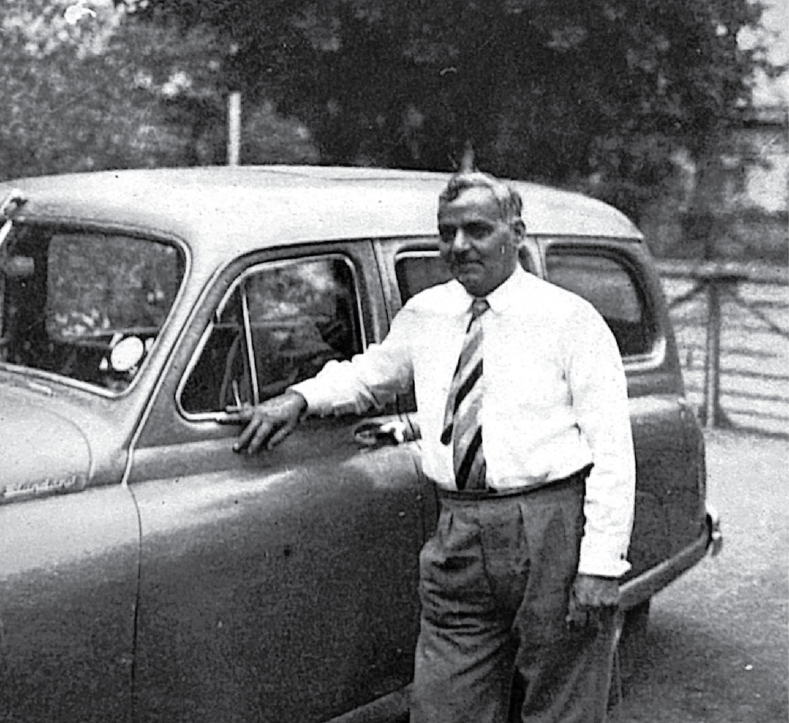 T.W. Talkwalkar standing in front of a  car in 1952.