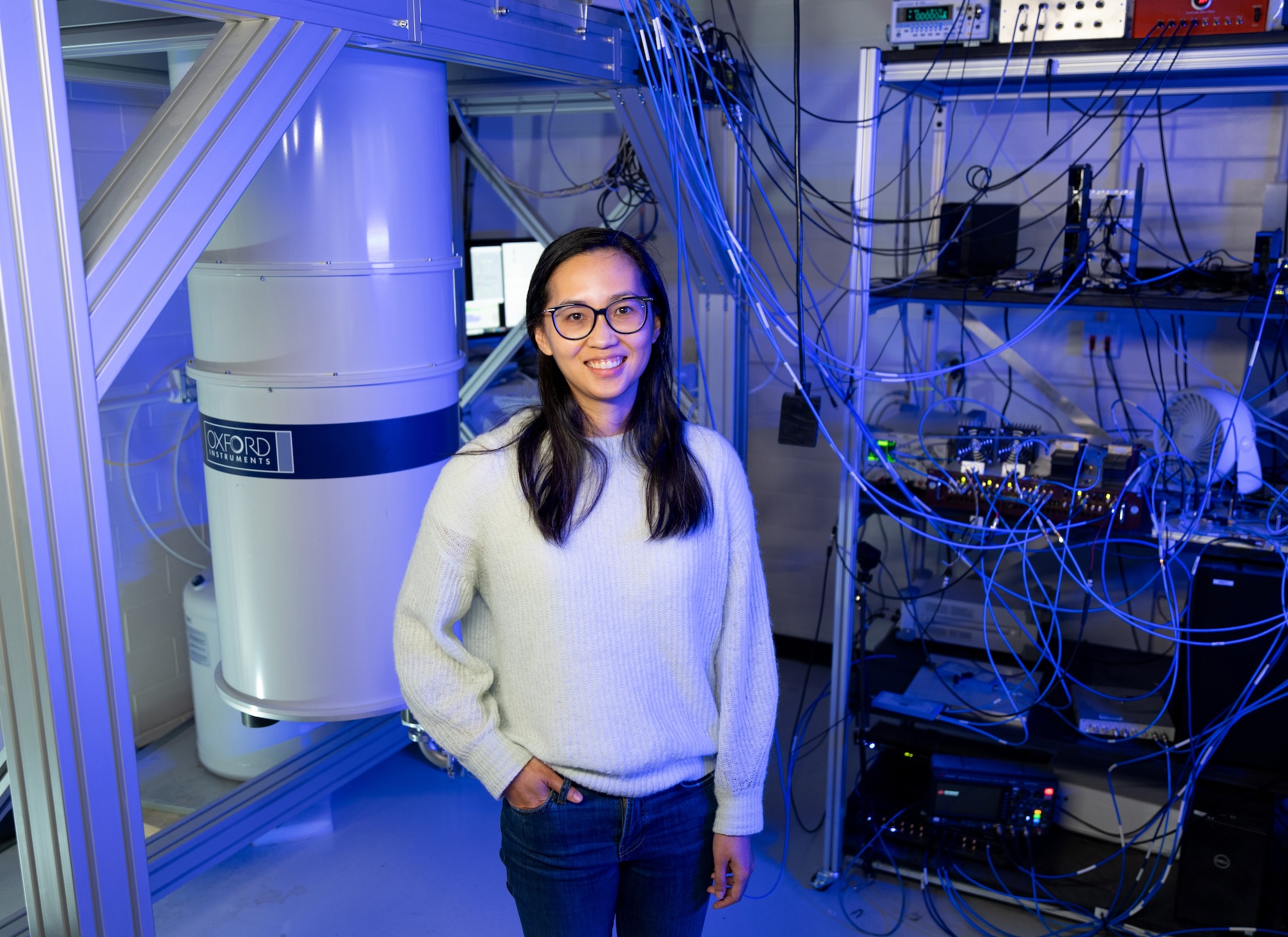 Physics professor Angela Kou works stands in front of equipment in one of her labs at the Materials Research Lab.