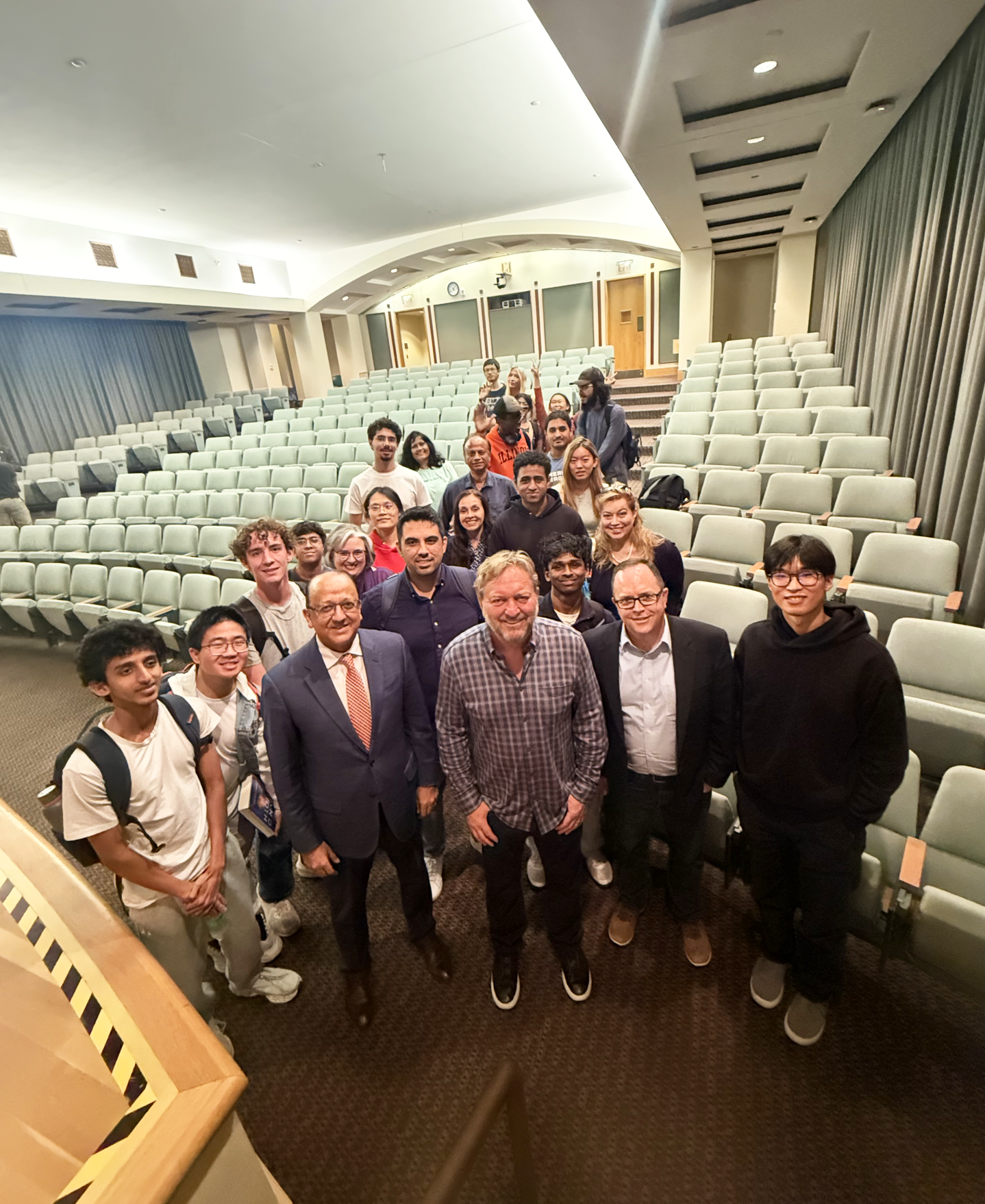 Dan Caruso poses with students and Grainger Engineering leadership inside a lecture hall.