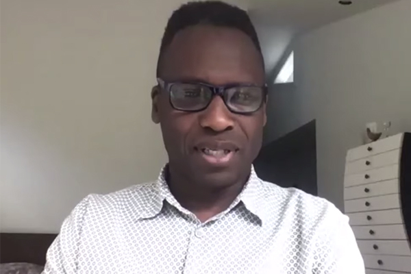 A man in a polka dot button down looking at the camera for a video call.