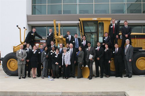 Hoeft T&M students pose with the Hoefts next to large construction equipment