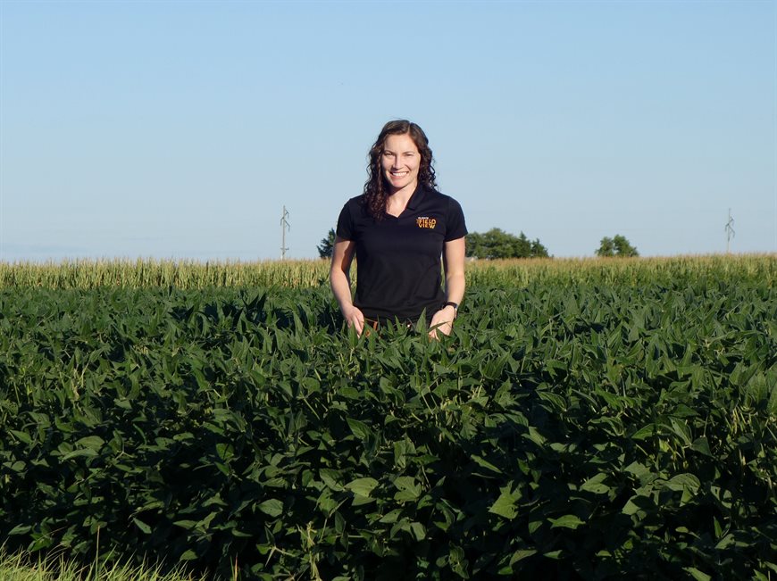 Samantha Knoll poses in a field of soybean plants
