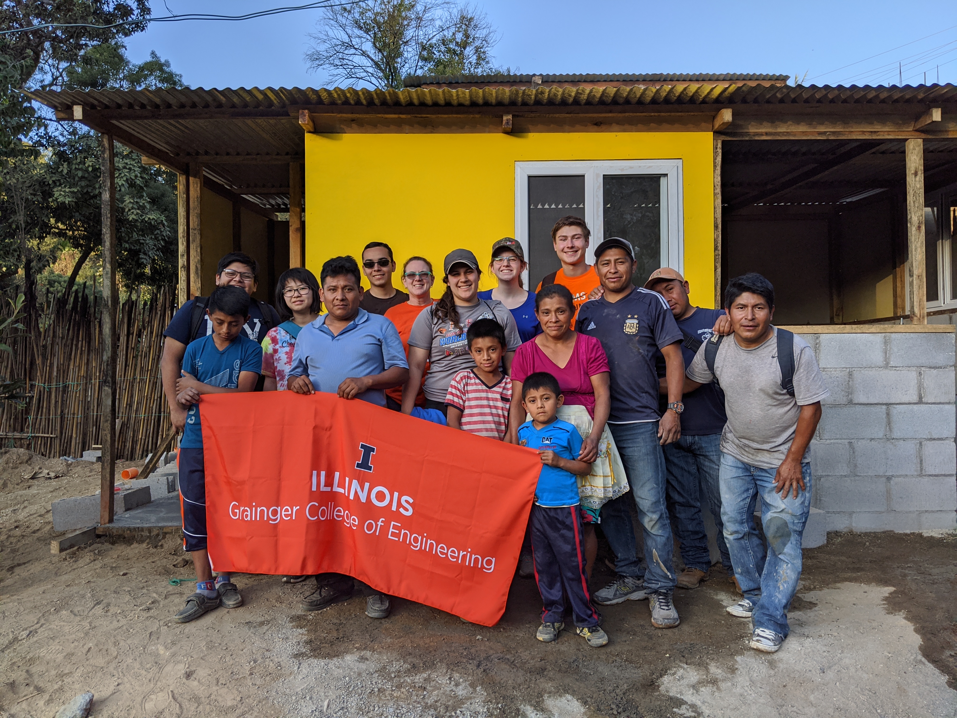 A group of people holding a Grainger Engineering flag.