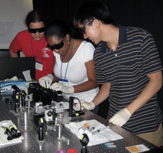CPLC graduate student, Lance Min (right) with summer school students Vanessa Ducas (middle) and Christian Osseforth (left) explaining a dual optical trap apparatus for measuring bacterial swimming.