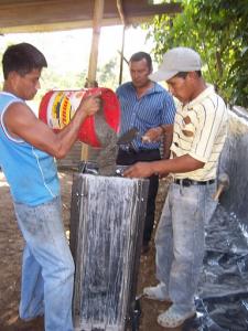 Guatemalan construction workers pouring concrete in biosand filter mold.
