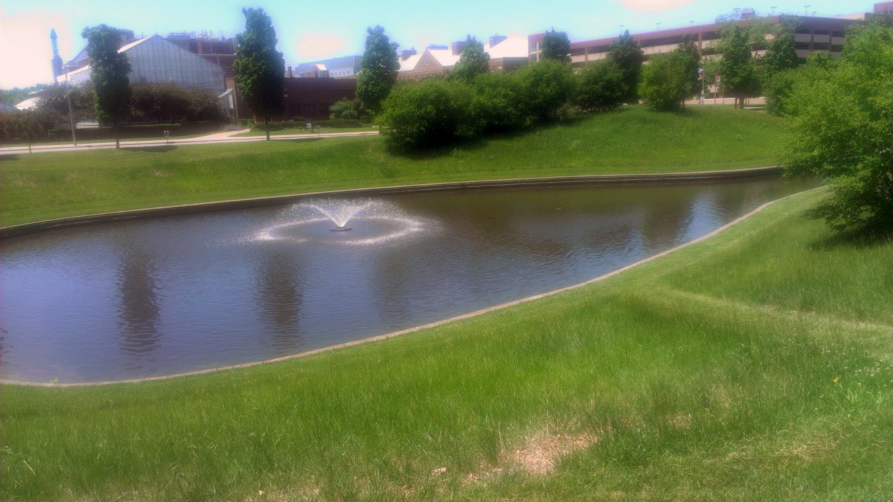 Artist's rendering of green infrastructure including an office building, farmstead, rolling grassy hills and a lake