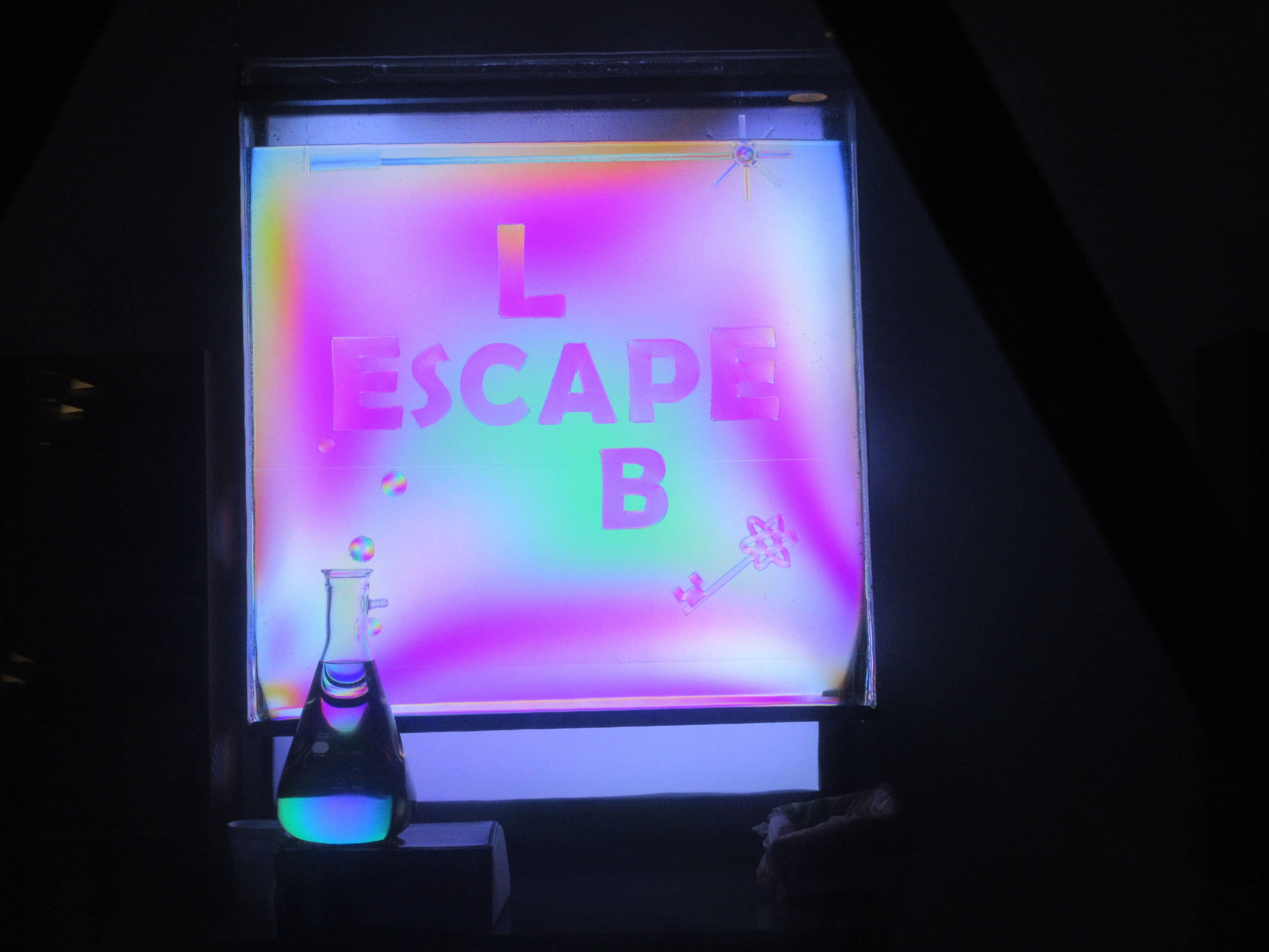 Chiral corn-syrup molecules polarize light, in a tank with the LabEscape logo.