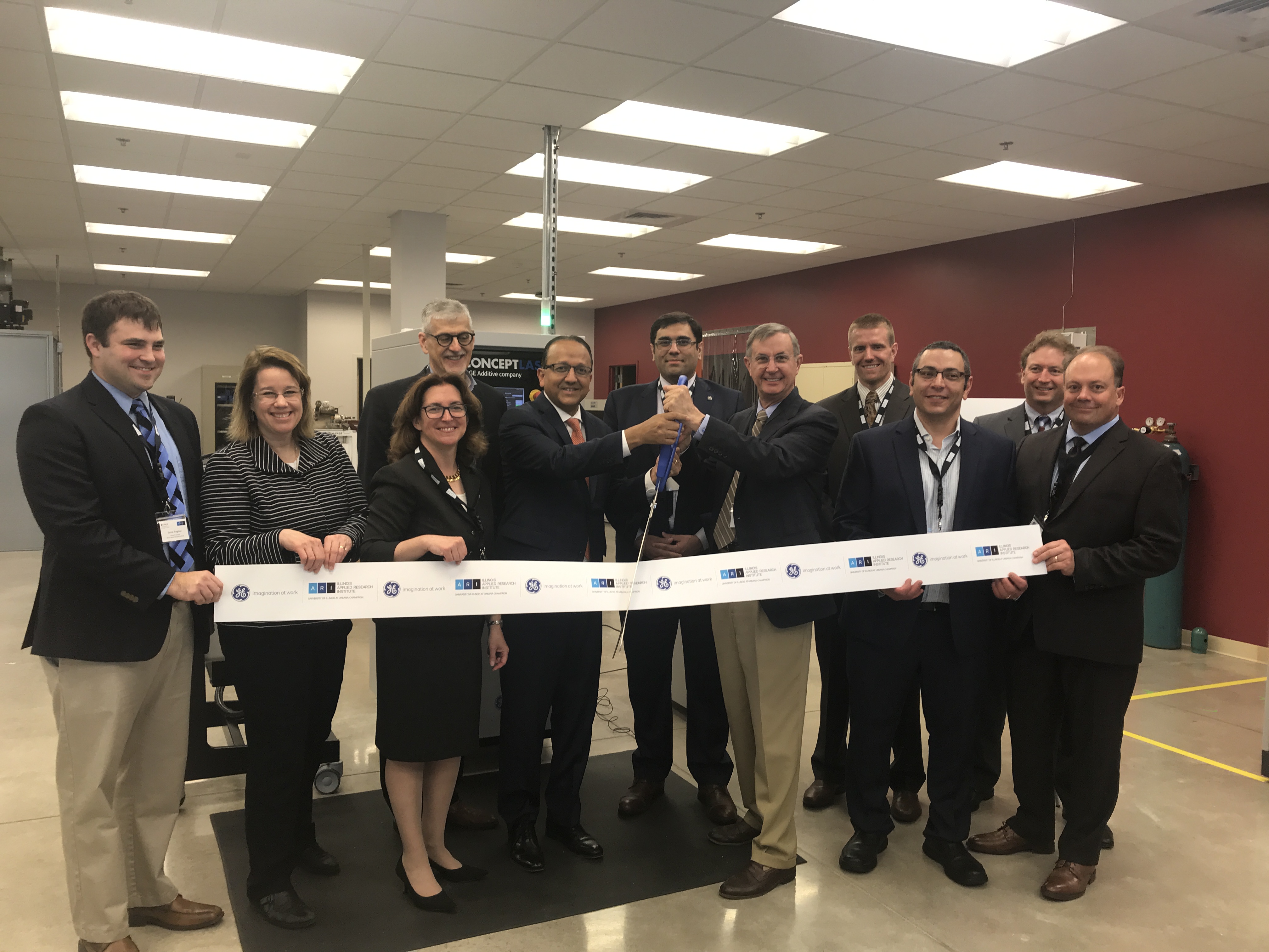 Dignitaries took part in the ribbon cutting ceremony for the Concept Laser Mlab 100R direct metal laser melting (DMLM) additive manufacturing system on April 25, 2019 at the Applied Research Institute's light manufacturing facility. They included Daniel Krogstad, Research Scientist, ARI; Susan Martinis, Interim Vice Chancellor for Research at Illinois; Jennifer Bernhard, Interim Director, Applied Research Institute; Magdi Azer, Associate Director for Manufacturing Science, ARI; Rashid Bashir, Dean, College of Engineering; Behrang Poorganji, Director of Materials Technology, GE Additive; Brad Mottier, Vice President and General Manager for Business and General Aviation and Integrated Systems, GE Aviation; James Ward, Cybersecurity Software Engineering Director, GE Aviation; Mohamed Aboukhatwa, Research Scientist, ARI; Shawn Oâ€™Day, Marketing Leader for Business and General Aviation and Integrated Systems, GE Aviation; and Anthony Denhart, Global University Relations Director, GE