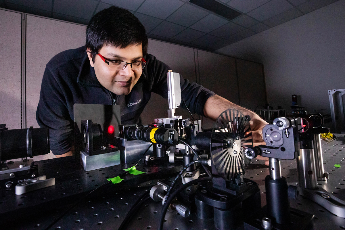 Male graduate student doing laser research at cancer center in Beckman Institute.