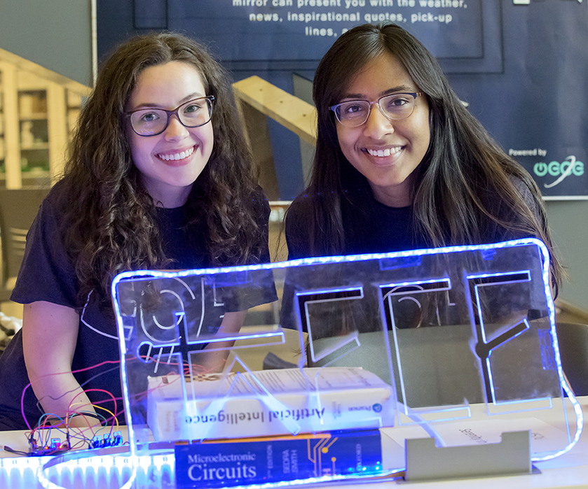 Two female undergraduate students demonstrate a smart mirror at the Electrical and Computer Engineering building during the Engineering Open House.