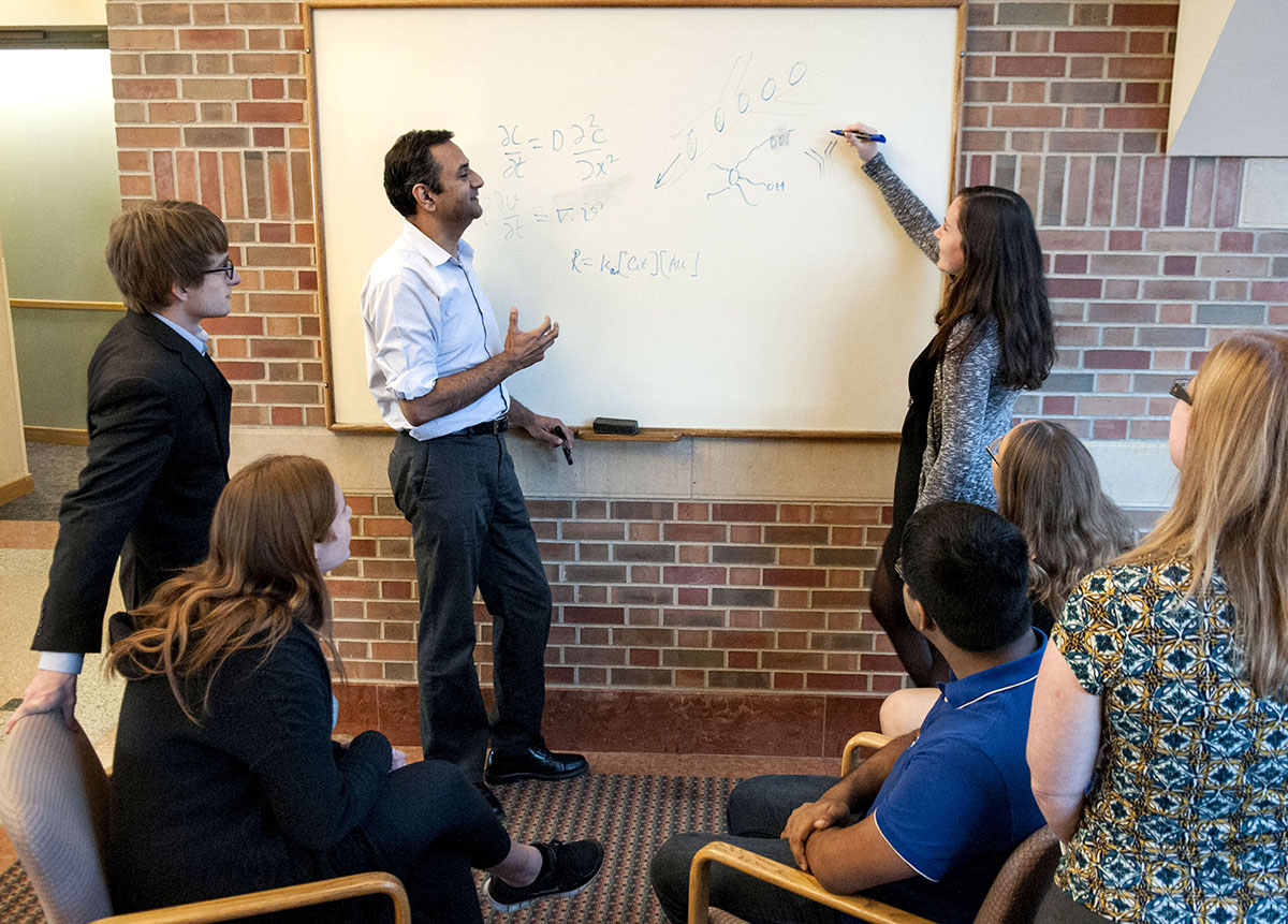 Rohit Bhargava draws on a white board while a group of students watch