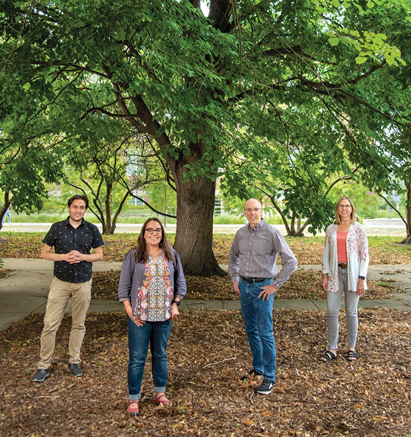 4 people pose in front of a tree