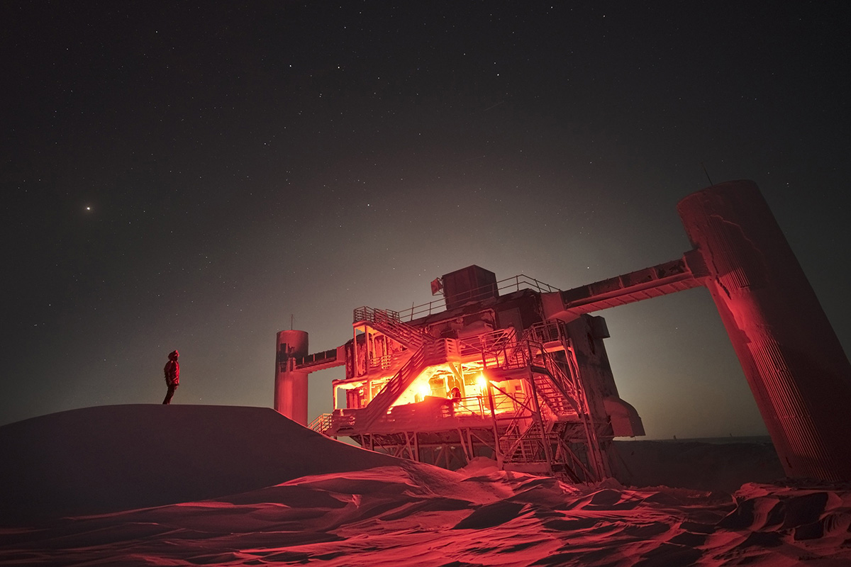 Person silhouetted against the night sky next to an illuminated building