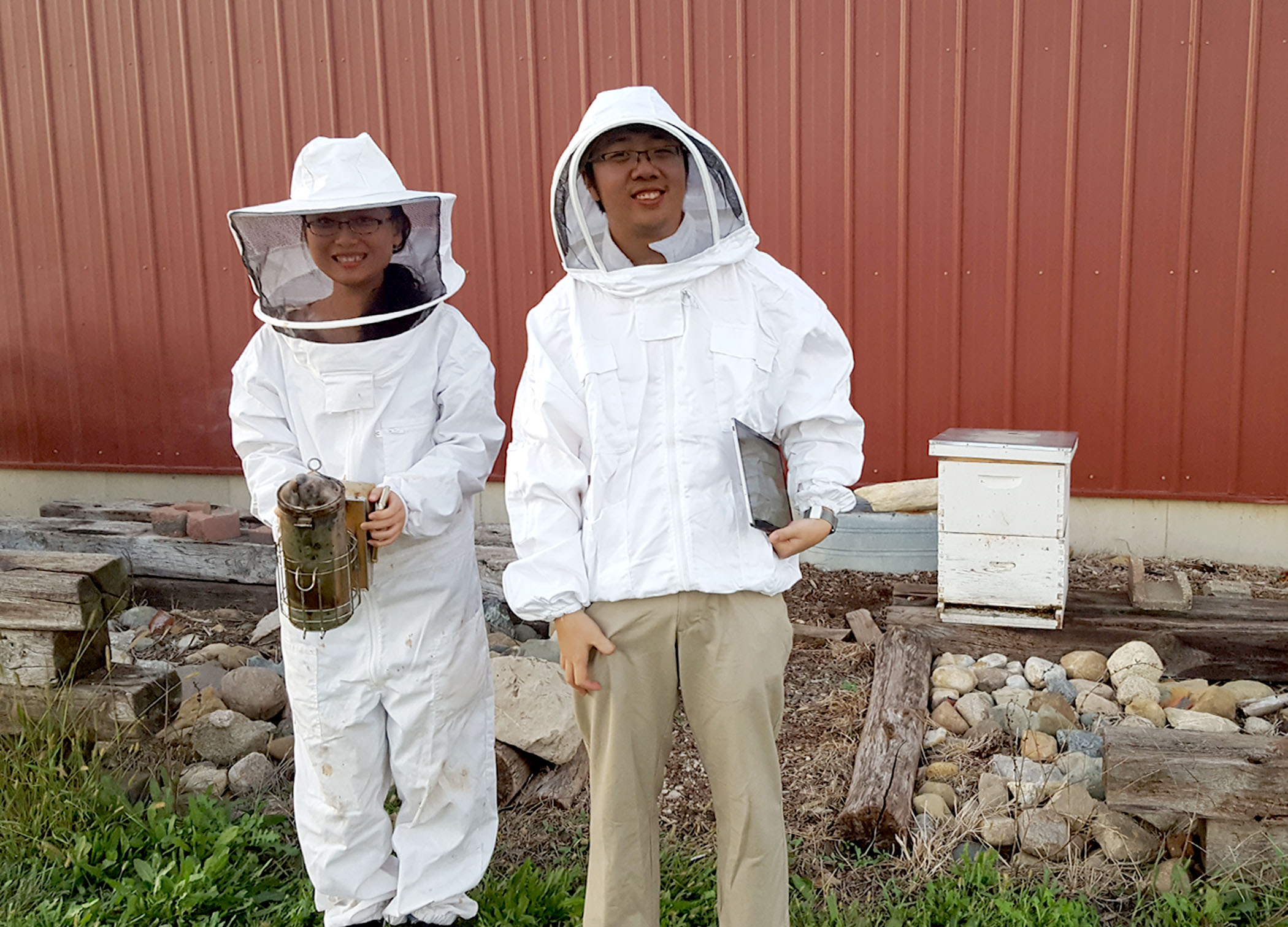 Xiaolin Wu (left) and Jimmy He suit up to install WaggleNet at Schmitz&amp;rsquo;s own beehive. &amp;nbsp;Photo by Chris Schmitz