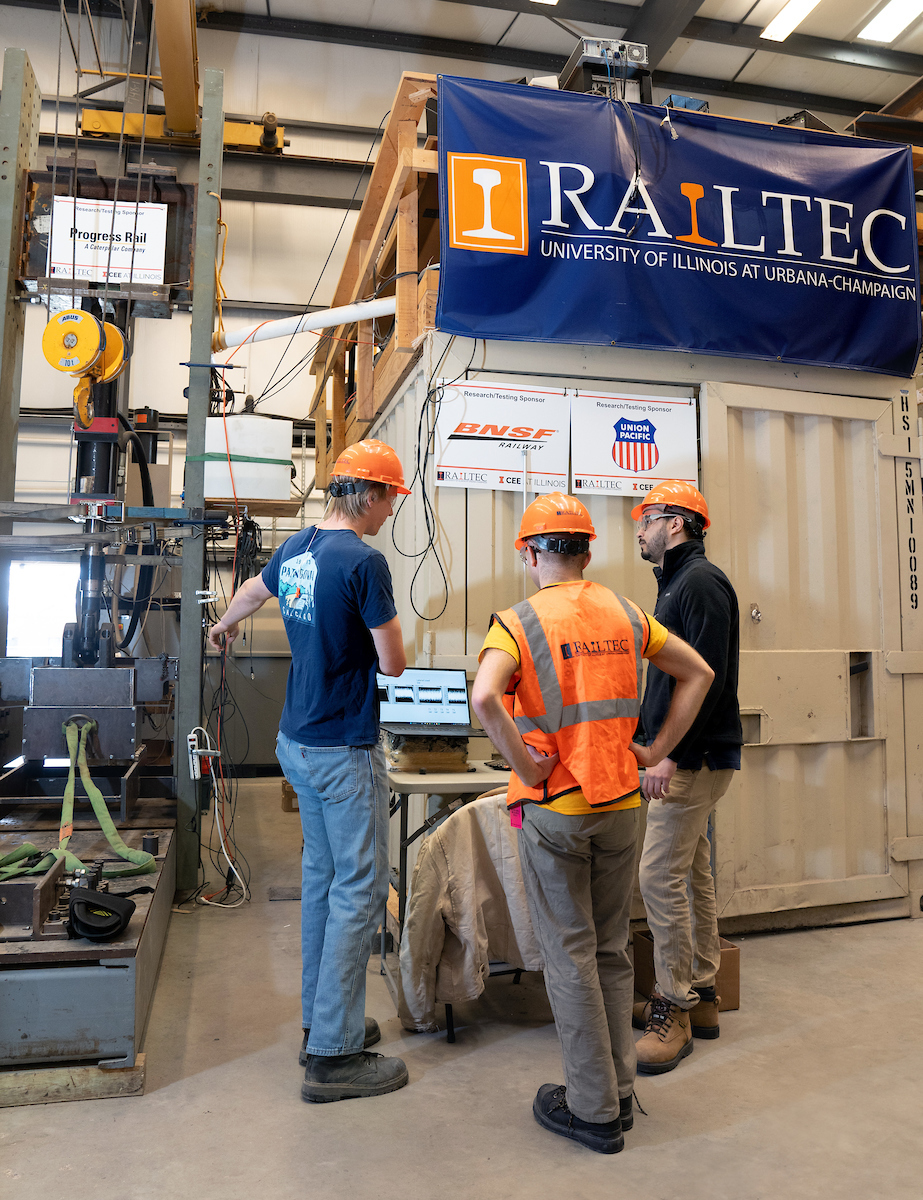 RailTEC's graduate research assistants, L-R, Coleman Froehlke, David Wasilewski and Jose Augusto Ramos work near the Large Scale Test Frame (LSTF) at the Research and Innovation Laboratory (RAIL) in Champaign.