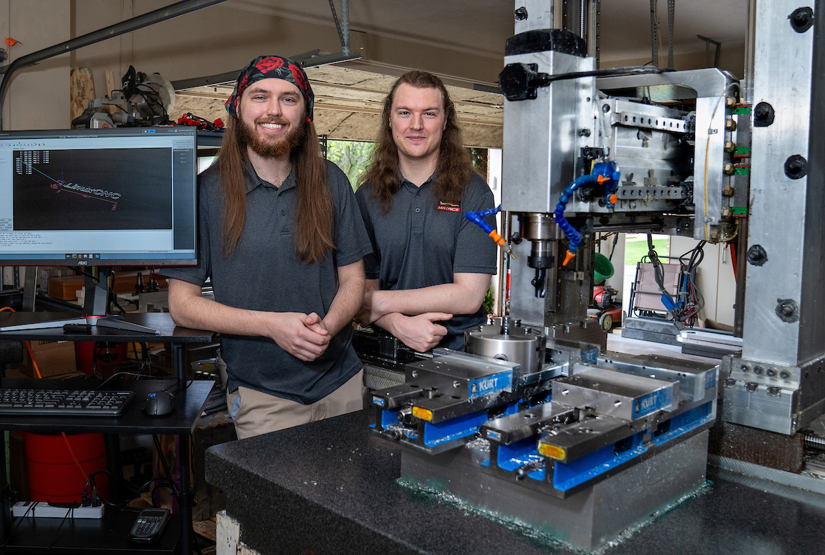 Twin brothers Robert, left, and Richard Mauge show off the CNC machine they built in their garage in Champaign.