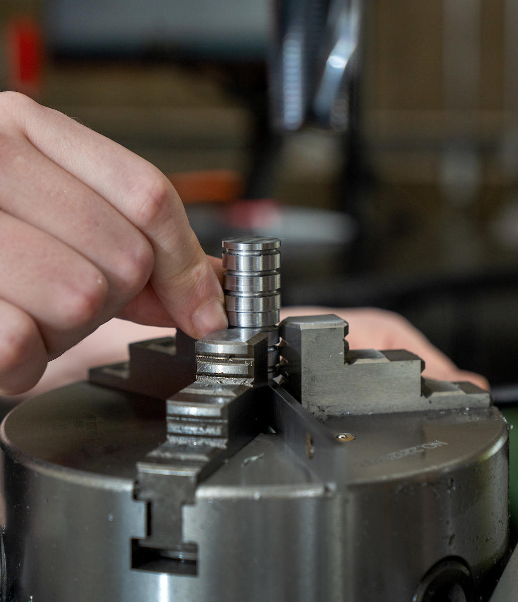 Robert Mauge clamps a part to a CNC machine.