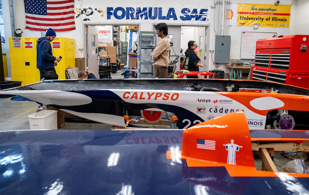 Illini Solar Car team in their workspace with solar cars in foreground.