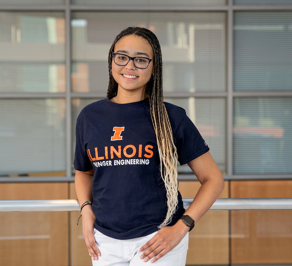 Saliyah As-Salaam (B.S. '26, Civil Engineering) received an Engineering Visionary Scholarship in academic year 2024. She is photographed in the HTML building wearing a blue Grainger Engineering t-shirt and white pants.